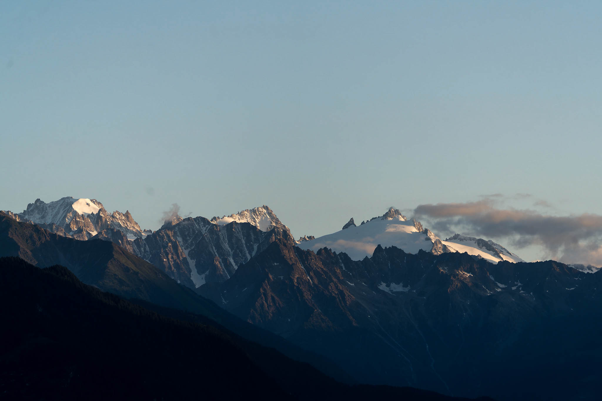 Panorama des sommets alpins éclairés par la lumière du soir.